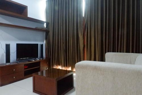 a living room with a couch and a tv and a table at Modern 2BR Apartment at Aryaduta Residence Surabaya Connected to CITO Mall By Travelio in Surabaya
