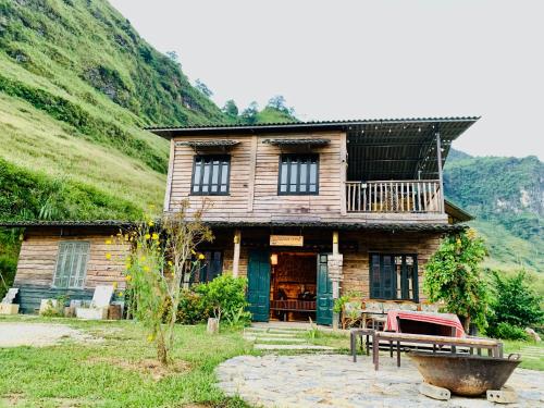 a wooden house with a bench in front of it at Du peak home in Làng Cac