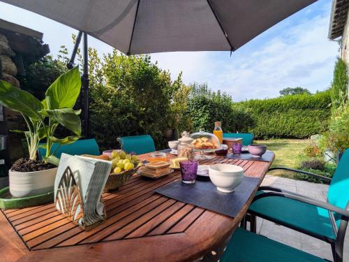 a wooden table with an umbrella on a patio at Maison d'hôtes rénovée avec table d'hôte dans la campagne Altiligérienne - FR-1-582-522 in Saint-Victor-sur-Arlanc