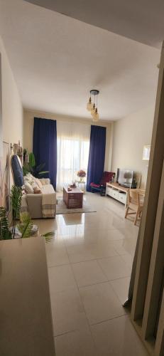 uma grande sala de estar com cortinas azuis e um sofá em 1001 night em Ras al-Khaimah