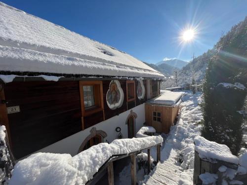 a house covered in snow with the sun behind it at Villa Evy in Mutters