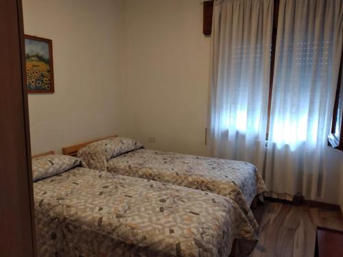 two beds in a hotel room with a window at Locazione Turistica Girasole in Porto Tolle