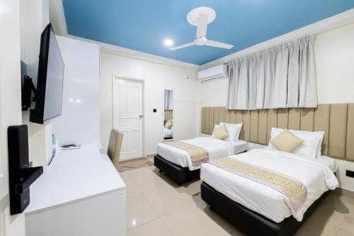 a hotel room with two beds and a flat screen tv at Air Residence 10978 in Hulhumale