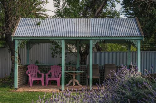 two pink chairs and a table in a gazebo at Jasmine's Barossa Valley Cottage in Lyndoch