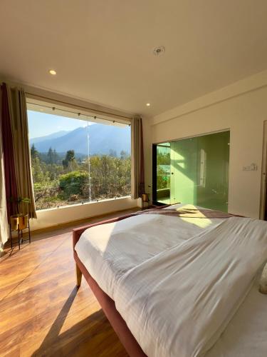a bedroom with a large bed and a large window at Baekar Stays in Manāli