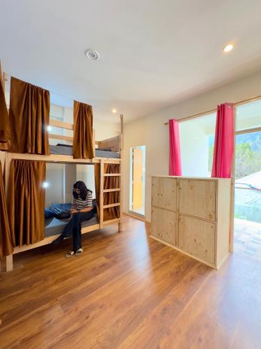 a person sitting in a bunk bed in a room at Baekar Stays in Manāli
