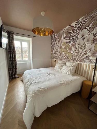 - une chambre avec un grand lit blanc et un mur fleuri dans l'établissement maison LE 3 haut de gamme centre historique, à Quimperlé