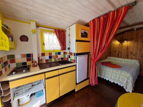 - une petite cuisine dans une maison de poupée avec un lit dans l'établissement Roulotte Esméralda: Séjour insolite au cœur de la nature, climatisée, parking privé, prêt de vélos - FR-1-590-502, à Bonnée