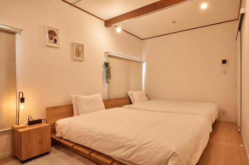 two beds in a room with white walls at 2Rooms Haneda in Tokyo