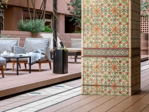a patio with chairs and a table with a patterned wall at Hotel The Celestine Tokyo Shiba in Tokyo