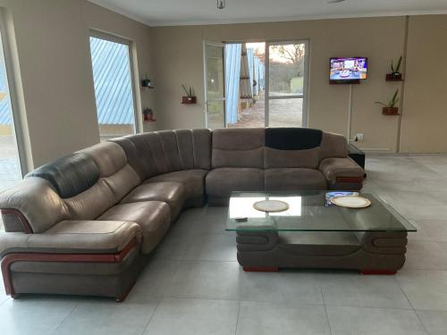 a brown leather couch in a living room with a table at Riverside Recreation Lodge in Katima Mulilo