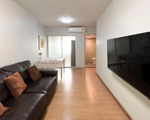 a living room with a black leather couch and a television at Tranquil Urban Retreat at Cheangwattana in Pak Kret