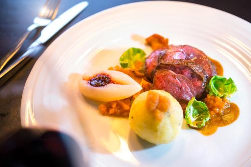 a white plate of food with meat and vegetables at Hotel Landgasthof König von Preussen in Marxzell