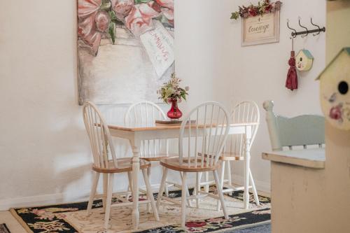 a dining room table with four chairs and a vase with flowers at Jasmine's Barossa Valley Cottage in Lyndoch