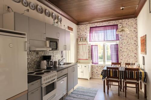 Una cocina con gabinetes blancos y una mesa con sillas. en Pikisaari Apartment, en Oulu