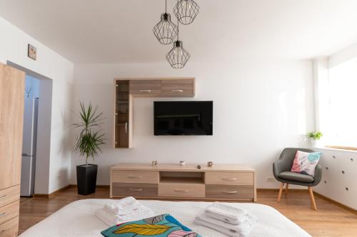 ein weißes Wohnzimmer mit einem TV und einem Stuhl in der Unterkunft Ten House in Piteşti