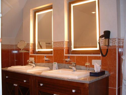 a bathroom with two sinks and two mirrors at Altstadthotel Bräuwirt in Weiden