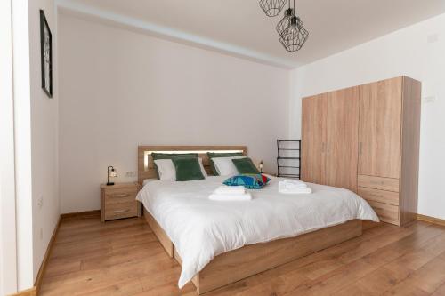 ein weißes Schlafzimmer mit einem großen Bett und einem Holzschrank in der Unterkunft Ten House in Piteşti
