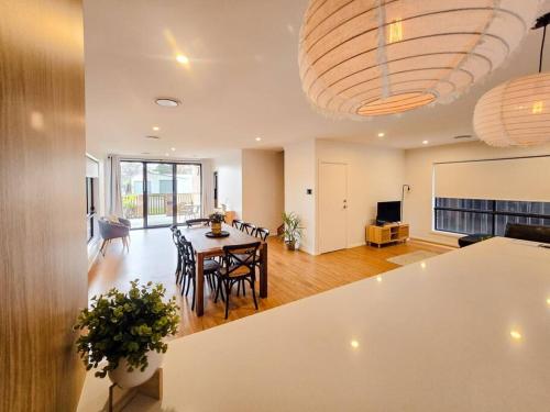 a dining room and living room with a table and chairs at Stylish Stay 4BR Central Wagga in Wagga Wagga