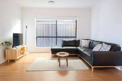 a living room with a black couch and a table at Stylish Stay 4BR Central Wagga in Wagga Wagga