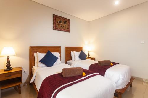 a hotel room with two beds and a clock on the wall at Naksa Homestay Sanur in Sanur