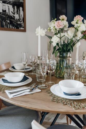 a wooden table with plates and glasses and a vase of flowers at Apres Ski Bachleda - LoftAffair Collection in Zakopane
