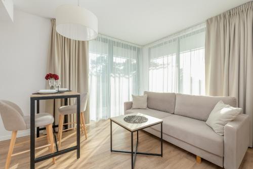 una sala de estar con un sofá y una mesa en Jantaris Apartments near Beach with Fitness by Noclegi Renters, en Mielno