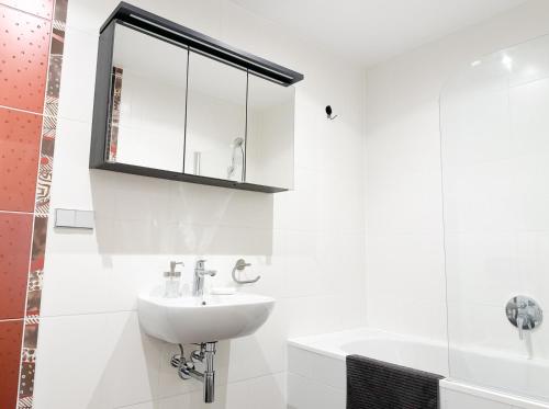 a white bathroom with a sink and a mirror at Elite centre, free parking, ultra-desirable 1 of 1, lux view in Rīga