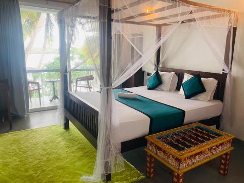 a bedroom with a canopy bed and a table at Lake Duwa Hotel in Ambalangoda