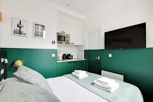 une chambre verte et blanche avec un lit avec des serviettes dans l'établissement Modern Studio with A-C - Near Montmartre, à Paris