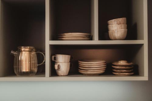 a cabinet filled with dishes and cups and plates at Les Doms d'Alfred - AKWADOM in Ten Eiken