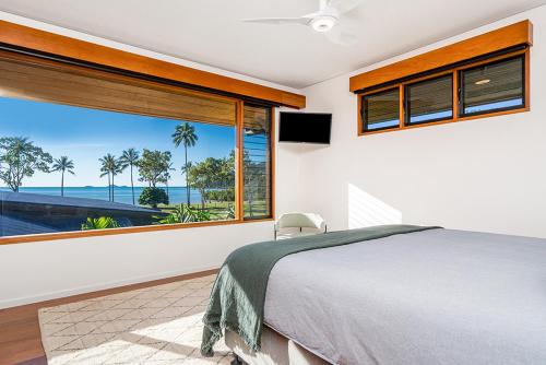 a bedroom with a large window with a view of the ocean at Yangaro in Airlie Beach