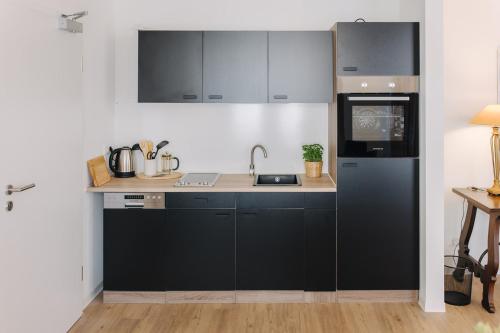 a kitchen with black cabinets and a sink at Markt 10 Apartments in Wanzleben