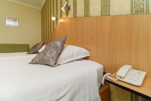 a bedroom with a bed with a phone next to it at Noviz Hotel in Plovdiv