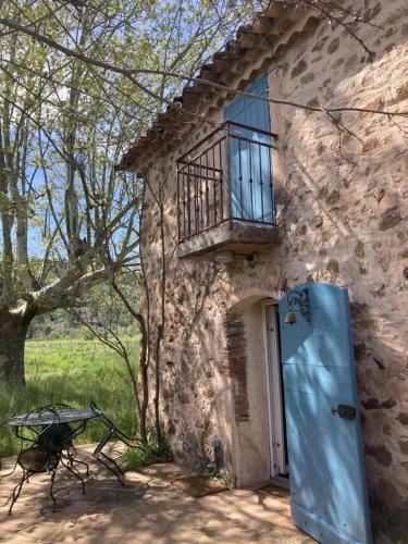 - un bâtiment en pierre avec une porte et un balcon dans l'établissement Gîte Superbe Bastidon Provençal isolé au cœur des vignes Bio, à Cuers
