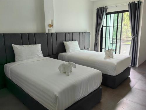 two beds with stuffed elephants on them in a room at Kiree River Hotel โรงแรมคิรีริเวอร์ in Ban Thong Pha Phum