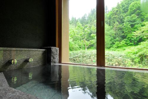 a bathroom with a window and a pool of water at Yamado in Nishiwaga