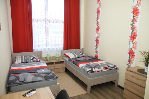 two beds in a room with red curtains at Pokoje nad Nysą Olszyna in Olszyna