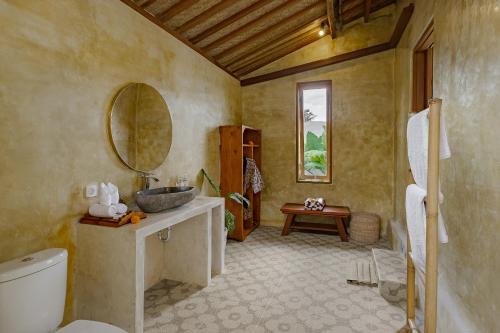 a bathroom with a sink and a toilet and a mirror at Pucuk Ubud Villa in Ubud