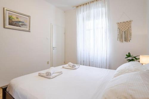 a white bedroom with a bed with towels on it at Apartment Bacvice in Split