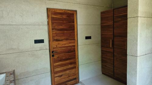 a wooden door in the corner of a room at Le Casa Lion Resort A Premium Resort In Sasan Gir in Sasan Gir