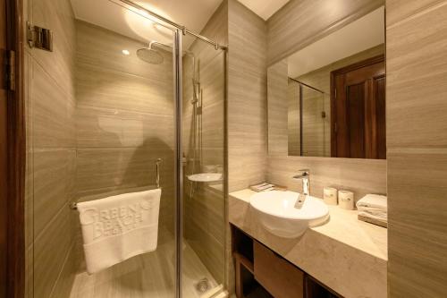 a bathroom with a sink and a glass shower at Green Beach Hotel Nha Trang in Nha Trang