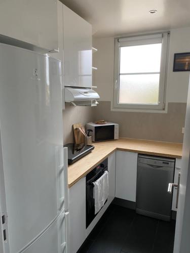 une petite cuisine avec un réfrigérateur et un micro-ondes dans l'établissement Appartement 2 chambres Versailles, à Versailles