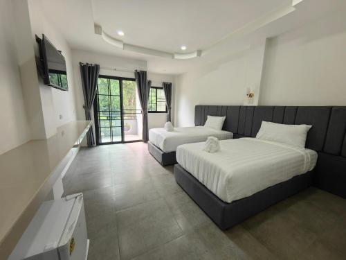 a hotel room with two beds and a television at Kiree River Hotel โรงแรมคิรีริเวอร์ in Ban Thong Pha Phum
