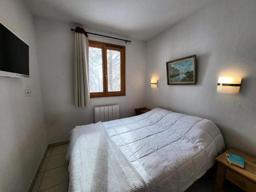une chambre avec un lit blanc et une télévision dans l'établissement Résidence Le Balcon Des Airelles - Agréable appartement avec une jolie vue MAE-9094, aux Orres