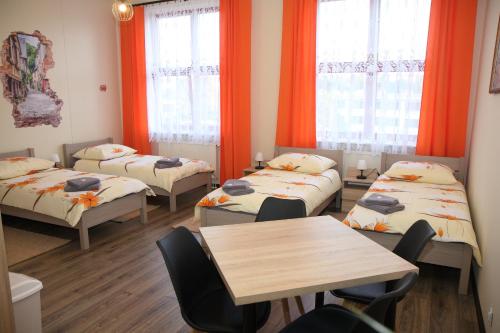 a room with four beds and a table and windows at Pokoje nad Nysą Olszyna in Olszyna