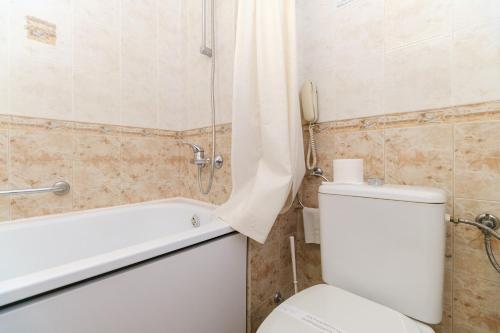 a bathroom with a white toilet and a bath tub at Noviz Hotel in Plovdiv