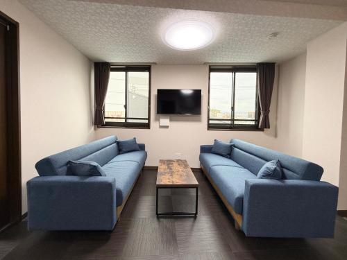 a living room with two blue couches and a table at PRISM Inn ZOSHIKI Kamata in Tokyo
