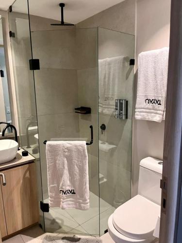 a bathroom with a glass shower stall with towels at Rooftop Pool Suites Vallarta in Bucerías