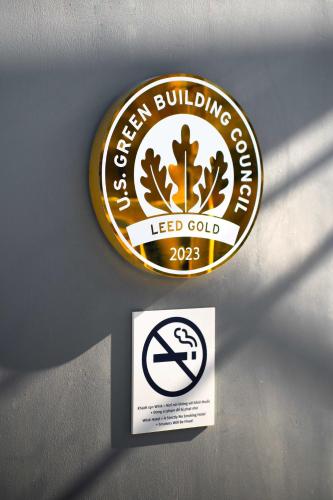 a sign for a green building company with a no smoking sign at Wink Hotel Tuy Hoa Beach - 24hrs Stay & Rooftop Pool Bar in Tuy Hoa